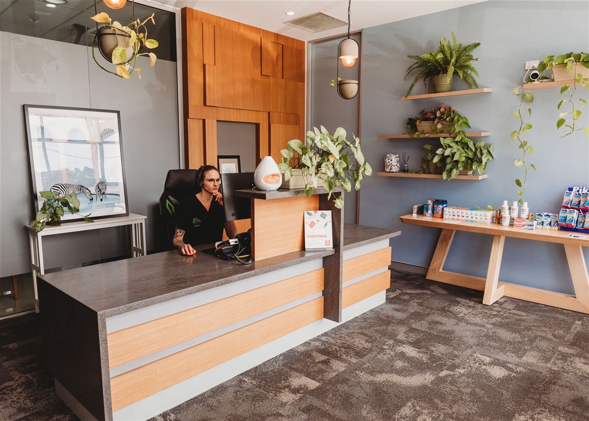 The front reception desk at Southside Dental Toowoomba, with timber finishes and hanging plants